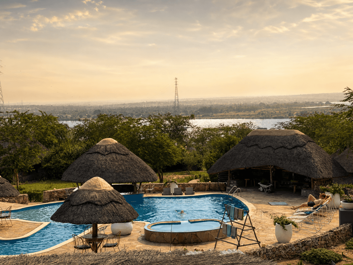 The elephant-shaped pool and hot tub at The Elephant Oasis with the Nile River visible in the distance at golden hour