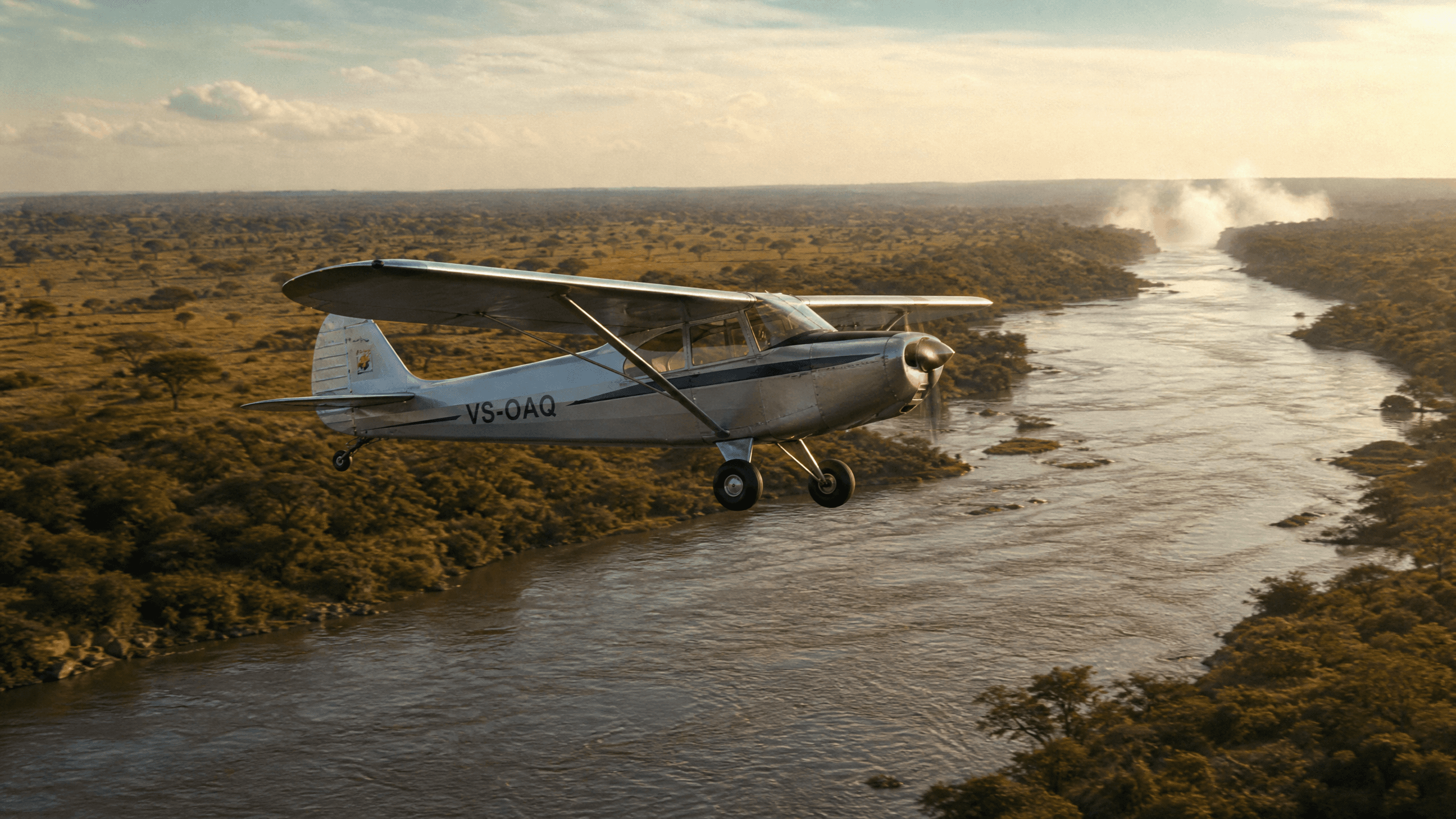 A vintage 1950s bush plane flying low over the Victoria Nile near Murchison Falls, Uganda, with the falls visible as mist in the distance